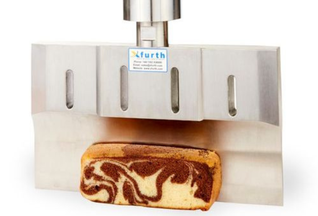 A loaf of marbled cake being precisely sliced by an ultrasonic food cutting machine, showcasing xfurth's advanced technology for clean and accurate cuts in food production.