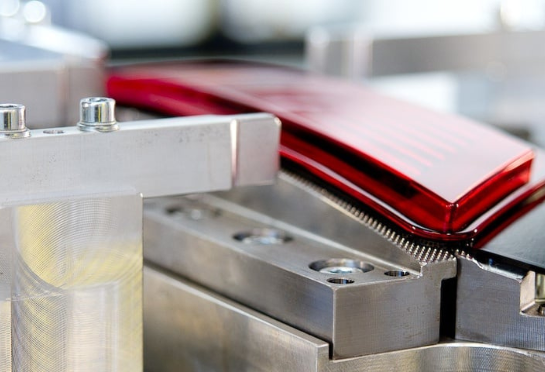 Plastic automotive component undergoing vibration welding in a precision metal fixture.